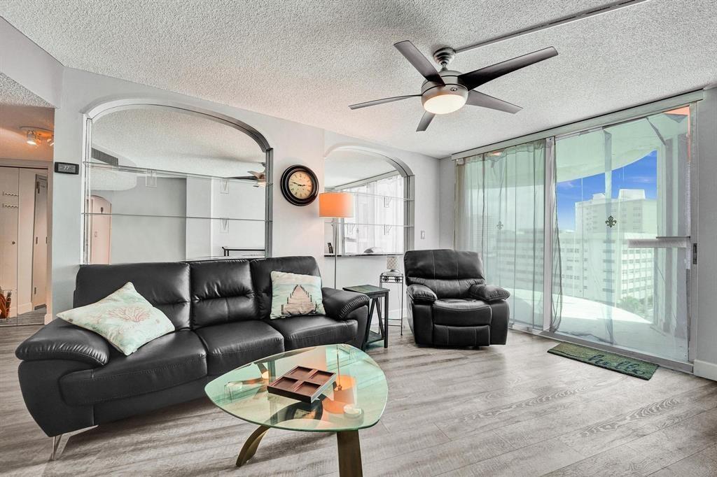 100 Golden Isles Drive, Unit 815 Hallandale Beach, FL 33009 - Photo 22 of 42 a living room with furniture a clock and a large window