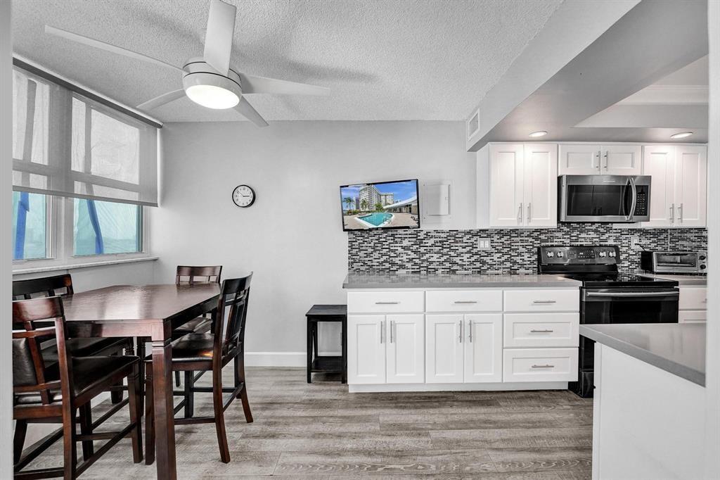 100 Golden Isles Drive, Unit 815 Hallandale Beach, FL 33009 - Photo 25 of 42 a kitchen with stainless steel appliances kitchen island granite countertop a table chairs sink and cabinets