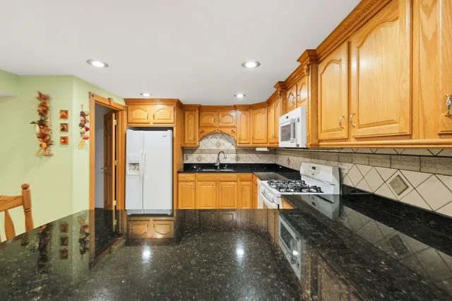 a kitchen with stainless steel appliances granite countertop a refrigerator a stove and a sink with wooden floor