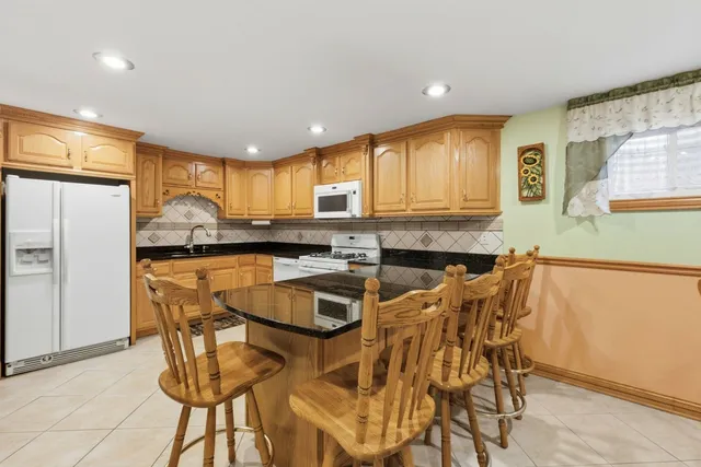 a kitchen with granite countertop a stove a sink and a refrigerator