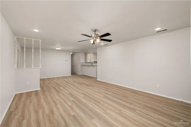 a view of empty room with wooden floor and ceiling fan