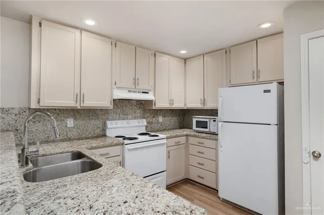 a kitchen with white cabinets sink and refrigerator