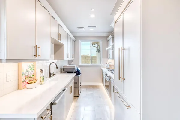 a kitchen with a sink appliances cabinets and a window