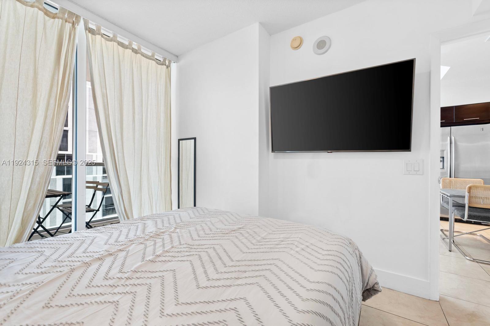 41 Southeast 5th Street, Unit 510 Miami, FL 33131 - Photo 16 of 38 a bedroom with a bed and a flat tv screen on the dresser