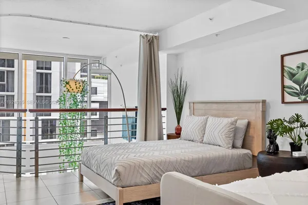 a bedroom with a large bed and a potted plant