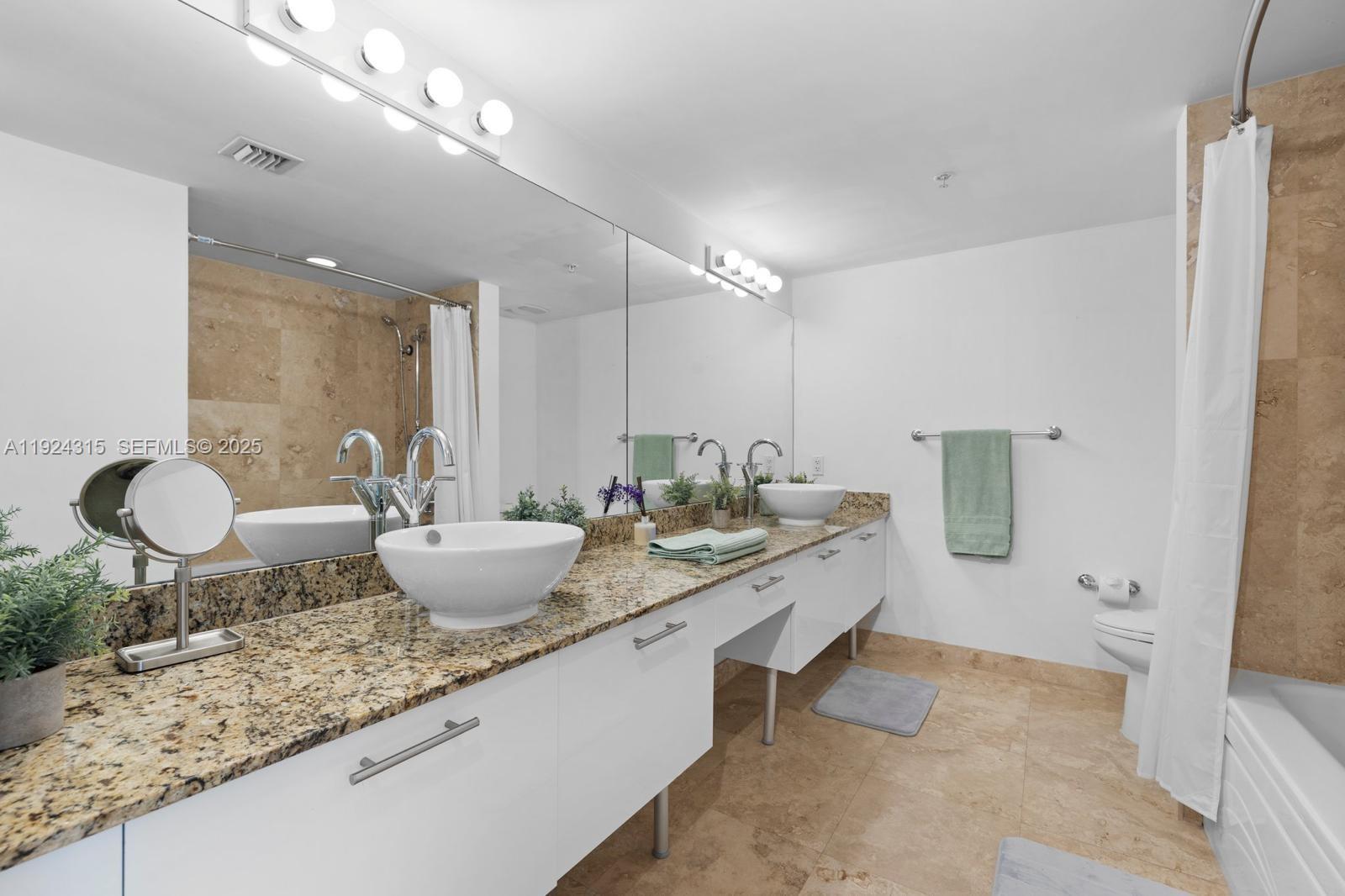 41 Southeast 5th Street, Unit 510 Miami, FL 33131 - Photo 27 of 38 a bathroom with a granite countertop sink and a mirror