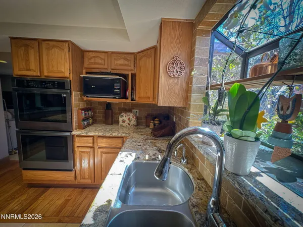 a view of a kitchen with stainless steel appliances granite countertop a stove top oven a sink and a granite counter top