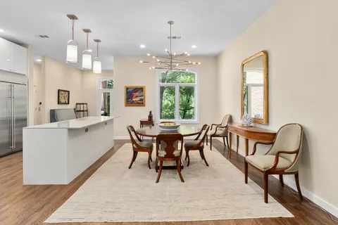 a dining room with chandelier and wooden floor