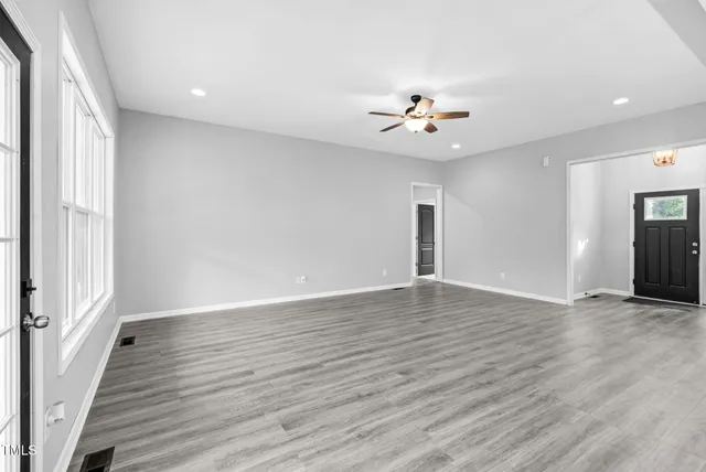 a view of an empty room with wooden floor and a window