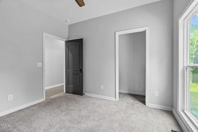 an empty room with a window and a fan