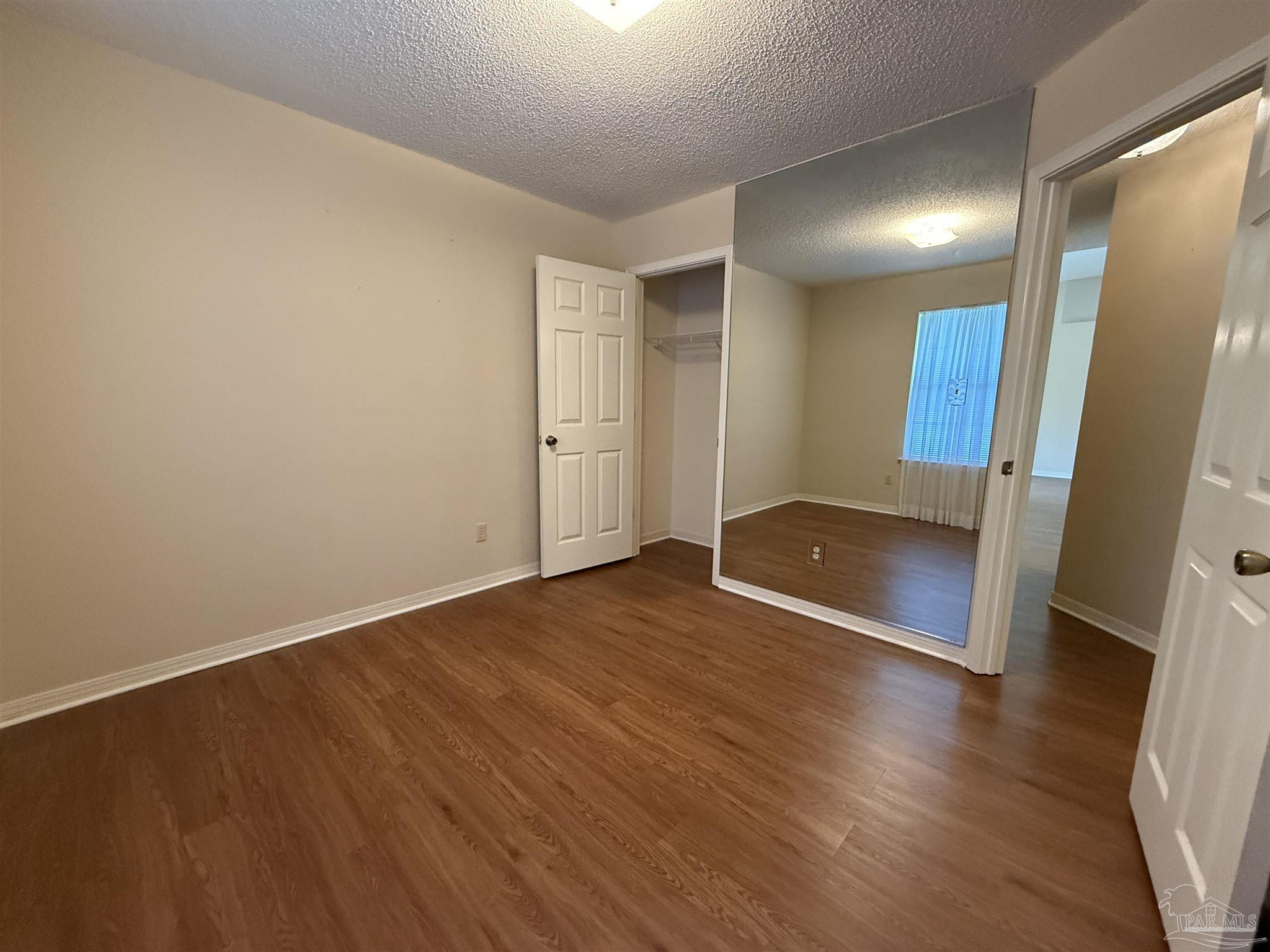 4814 Autumn Drive Pace, FL 32571 - Photo 25 of 52 an empty room with wooden floor and windows