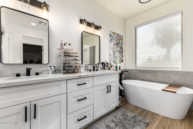 a bathroom with a bathtub a double vanity sink and mirror