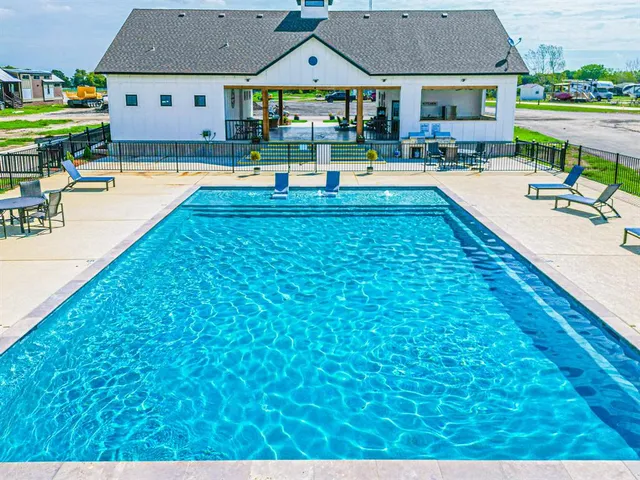 a view of swimming pool with lawn chairs and plants