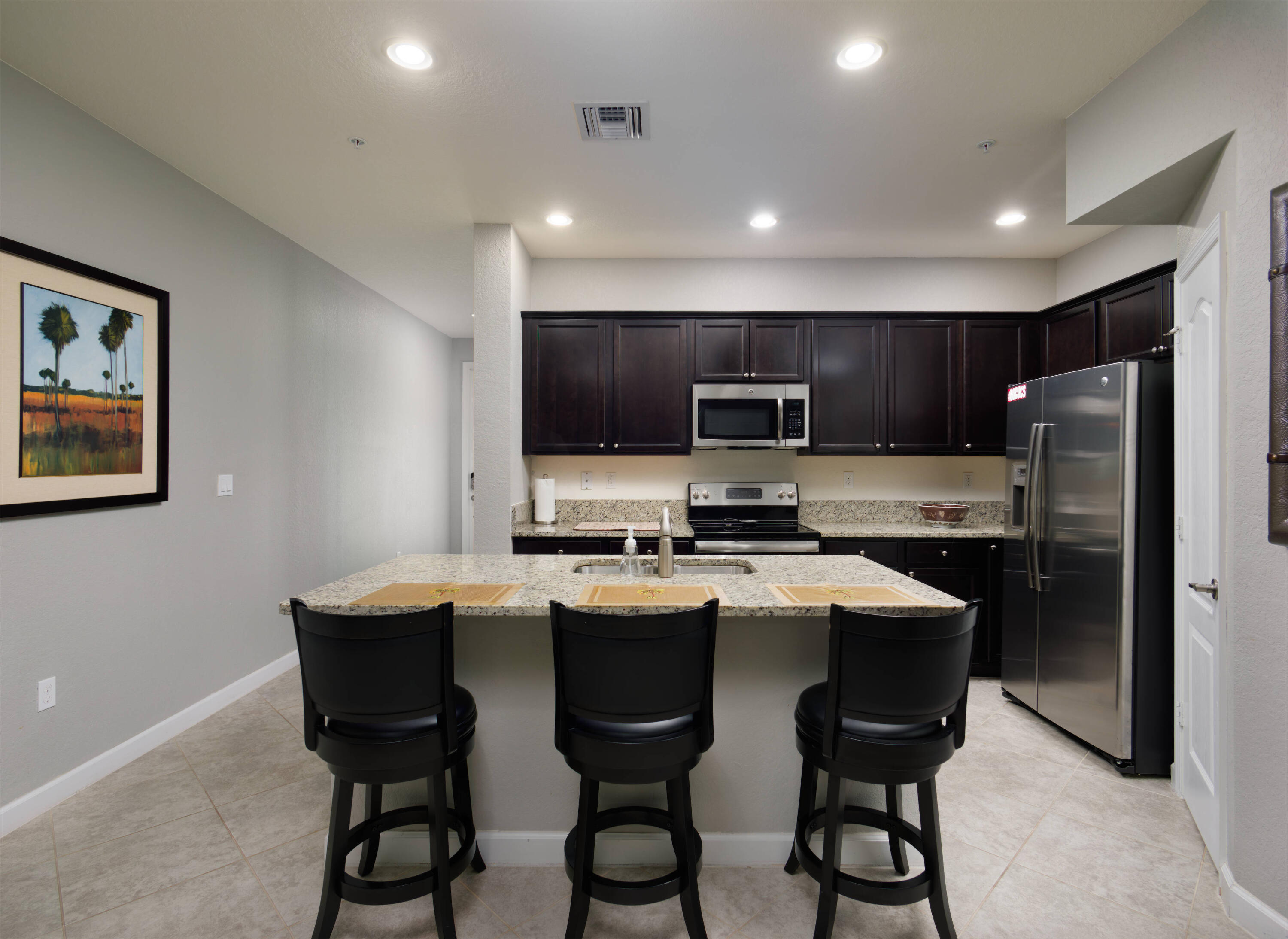 9674 Southwest Purple Martin Way Stuart, FL 34997 - Photo 3 of 21 a kitchen with cabinets a sink dishwasher a stove a refrigerator with a dining table and chairs