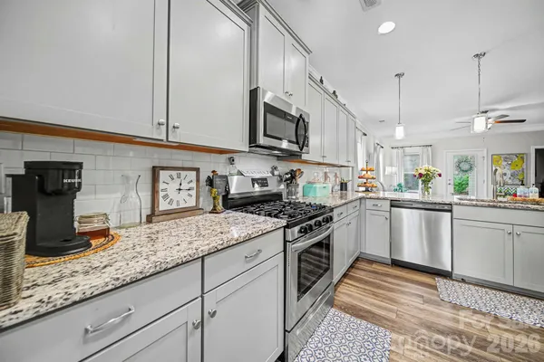 a kitchen with stainless steel appliances granite countertop a stove a sink and a microwave