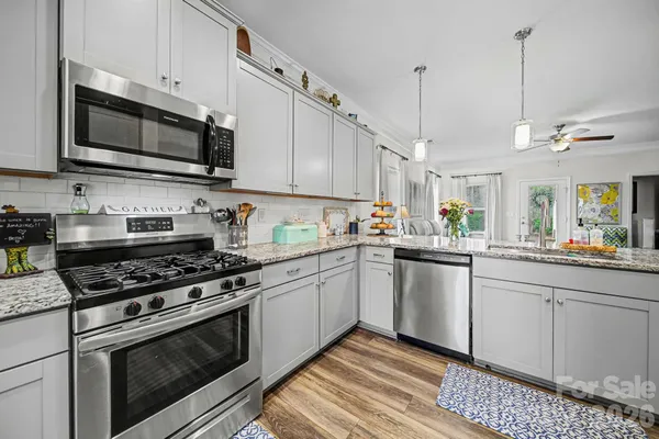 a kitchen with stainless steel appliances granite countertop a sink a stove a microwave and wooden cabinets