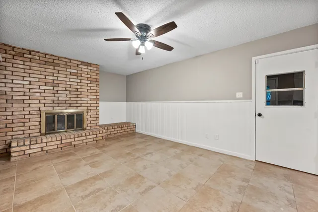 an empty room with windows and fireplace