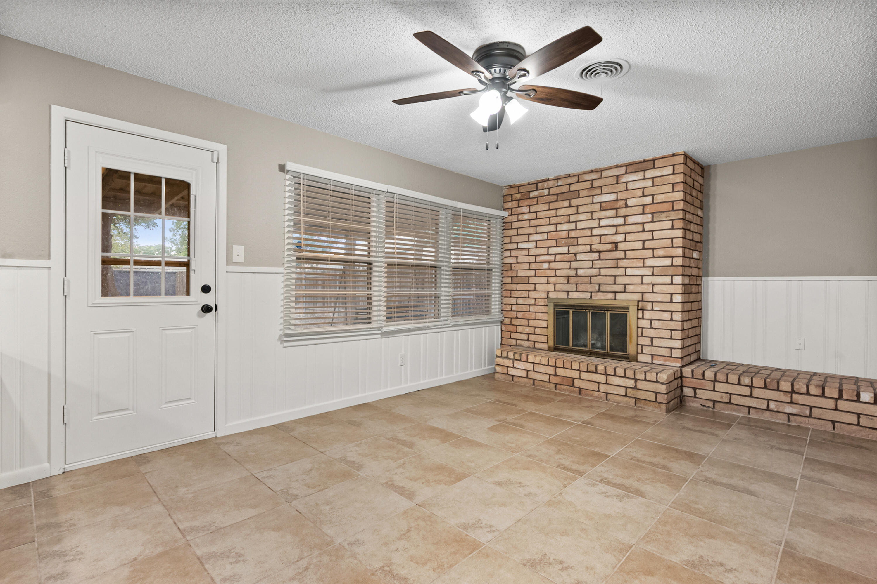 4915 11th Street Lubbock, TX 79416 - Photo 18 of 28 a view of a livingroom with a fireplace a ceiling fan and windows