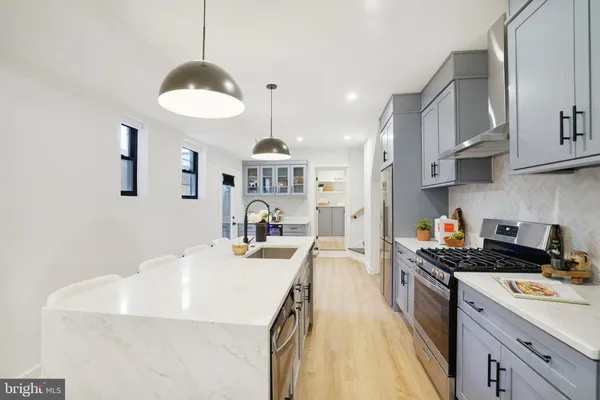 a kitchen with kitchen island granite countertop a sink a stove and cabinets