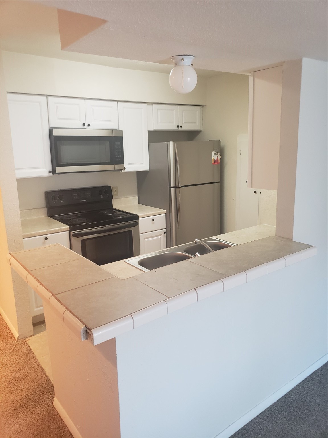16120 Stuebner Airline Road, Unit 603 Spring, TX 77379 - Photo 5 of 10 a kitchen with kitchen island a stove a refrigerator and a sink
