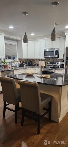 a kitchen with stainless steel appliances granite countertop a refrigerator a stove a sink dishwasher and a refrigerator with wooden floor