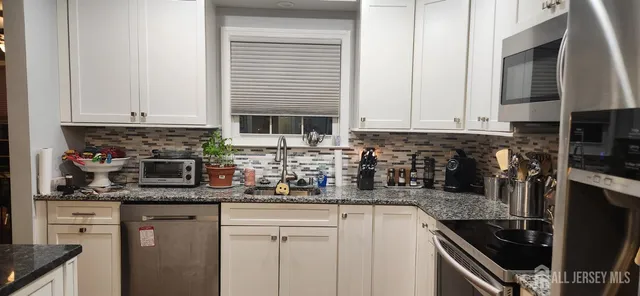 a kitchen with stainless steel appliances granite countertop a stove a sink and a refrigerator