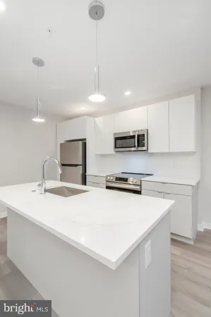 a kitchen with stainless steel appliances a sink a stove a microwave a center island and cabinets