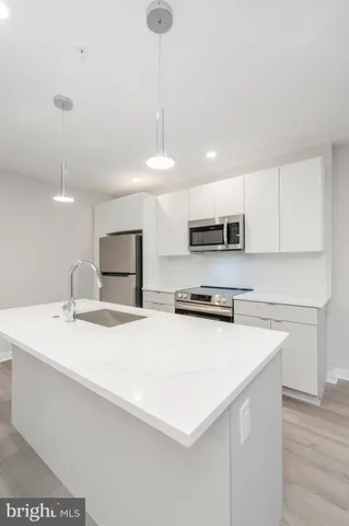 a kitchen with stainless steel appliances a sink a stove a microwave a center island and cabinets