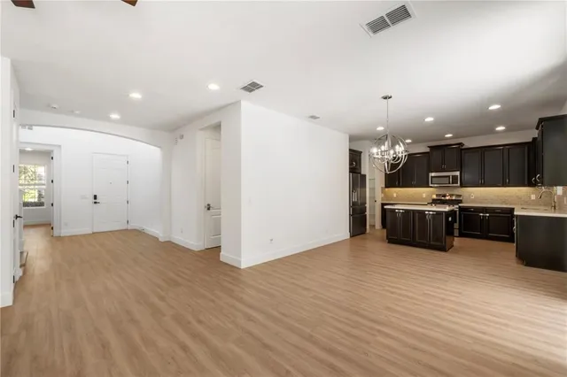 a room with stainless steel appliances kitchen island wooden floors a kitchen island a sink and a stove