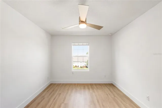 an empty room with wooden floor chandelier and windows