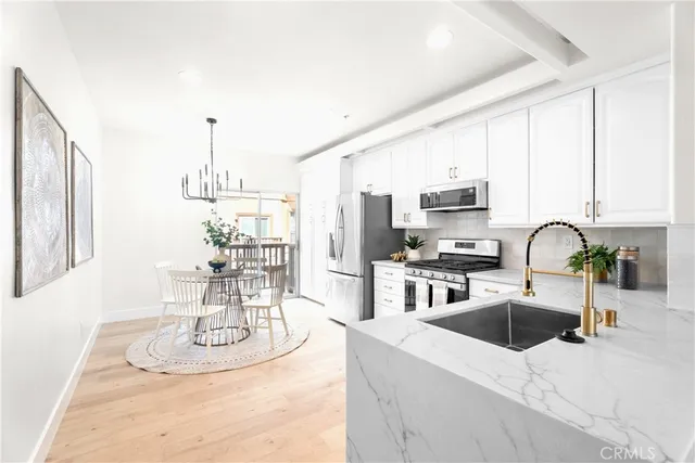 a kitchen with stainless steel appliances kitchen island granite countertop a sink dishwasher a stove a microwave oven a dining table and chairs with wooden floor