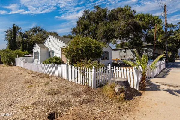 a view of a house with a small yard and wooden fence