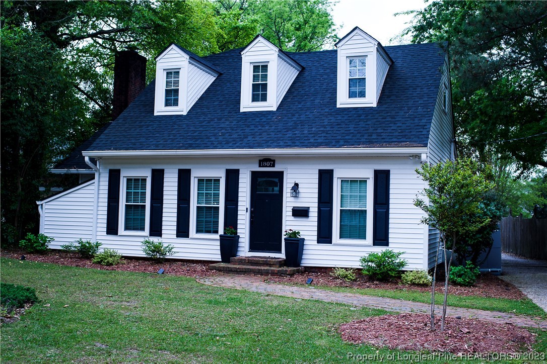 1807 Morganton Road Fayetteville, NC 28305 - Photo 2 of 37 a view of a brick house with a large windows and a yard with plants and large trees