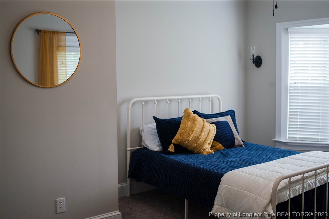 1807 Morganton Road Fayetteville, NC 28305 - Photo 23 of 37 a bed sitting in a bedroom next to a window and a mirror
