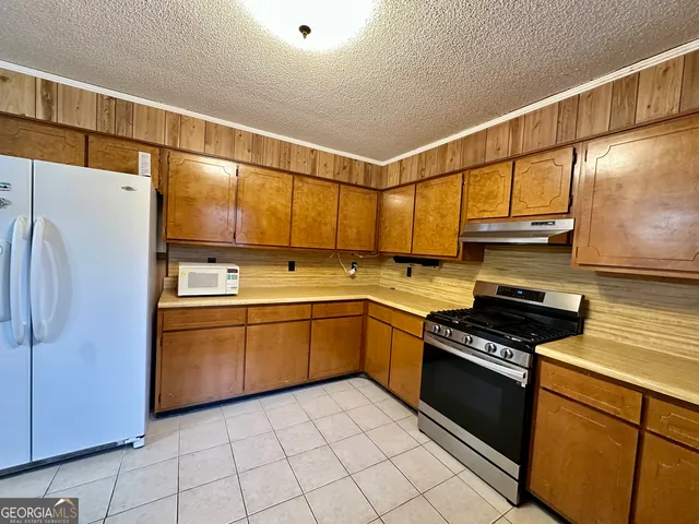 a kitchen with stainless steel appliances granite countertop a refrigerator and a stove top oven