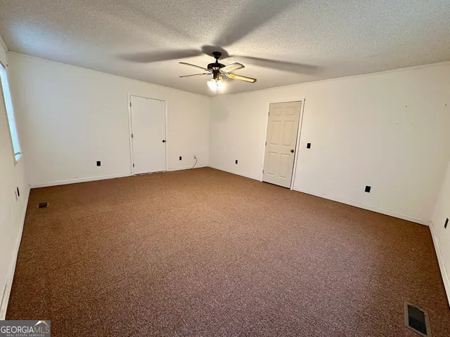 an empty room with a ceiling fan and a window