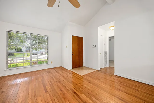 a view of an empty room with wooden floor and a window