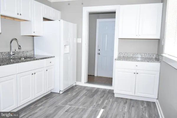 a kitchen with a sink a refrigerator and white cabinets