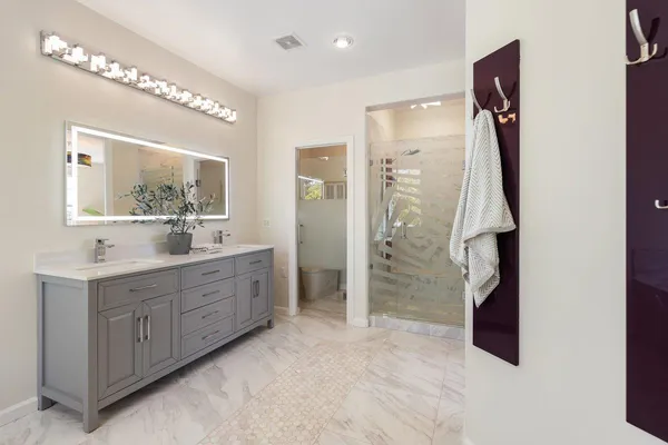 a spacious bathroom with a double vanity sink a mirror and shower