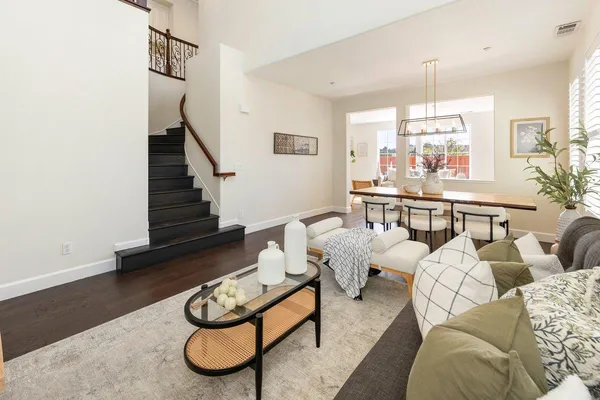 a living room with furniture couches and a dining table with wooden floor