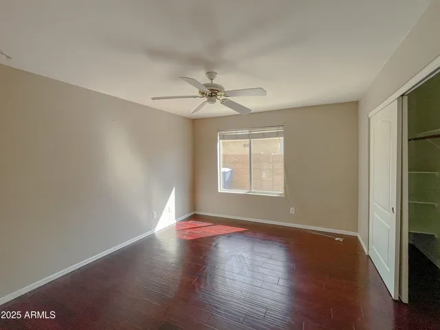 an empty room with wooden floor fan and windows