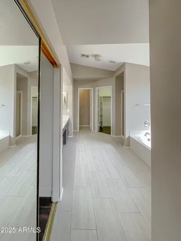 a view of a hallway with wooden floor and a bathroom