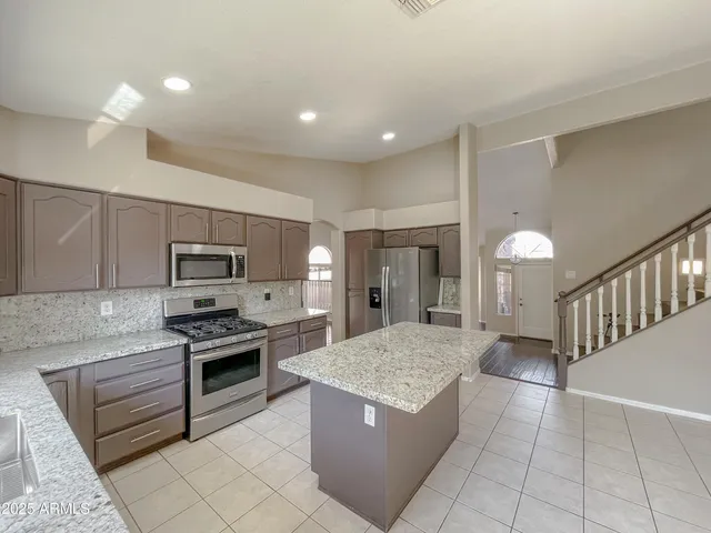 a kitchen with kitchen island granite countertop a stove and a sink