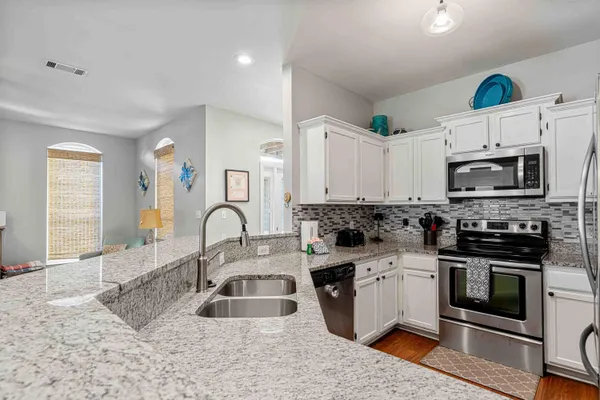 a kitchen with granite countertop a sink stainless steel appliances and cabinets