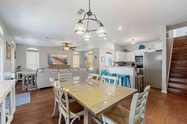 a view of a dining room and livingroom with furniture wooden floor a rug a fireplace and a chandelier