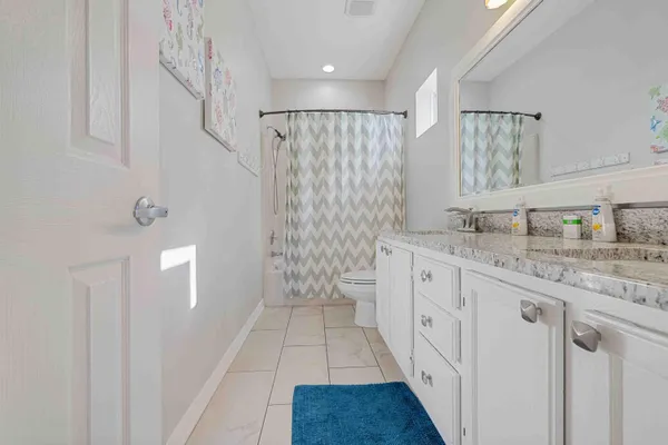 a bathroom with a granite countertop sink a toilet a mirror and shower