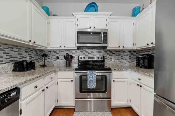 a kitchen with granite countertop white cabinets and stainless steel appliances