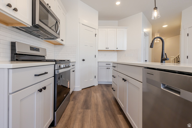 4812 Heartwood Road, Unit 424 Mapleton, UT 84664 - Photo 8 of 20 Kitchen featuring stainless steel appliances, dark wood-type flooring, backsplash, and white cabinets