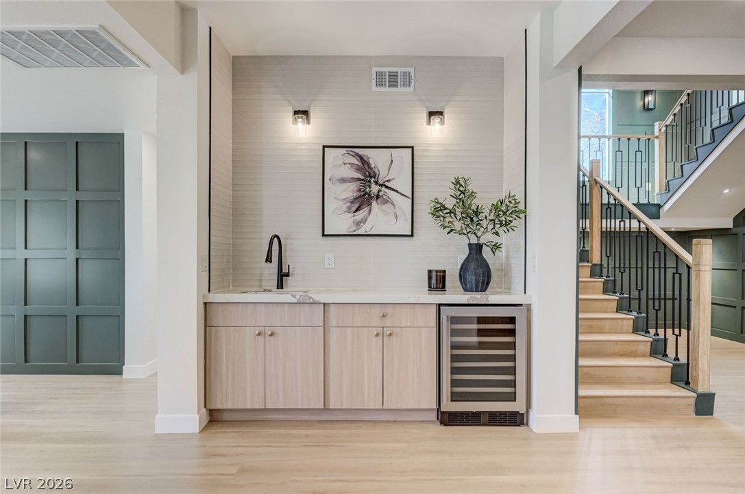 732 8th Street Boulder City, NV 89005 - Photo 1 of 15 Indoor wet bar with light wood finish cabinetry, wine cooler, light stone countertops, light wood-type flooring, and modern cabinets