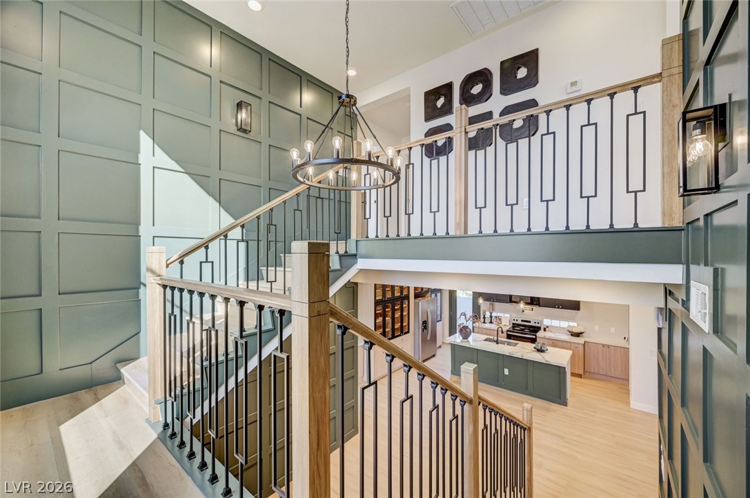 732 8th Street Boulder City, NV 89005 - Photo 5 of 15 Stairway featuring a decorative wall, a chandelier, wood finished floors, and a high ceiling